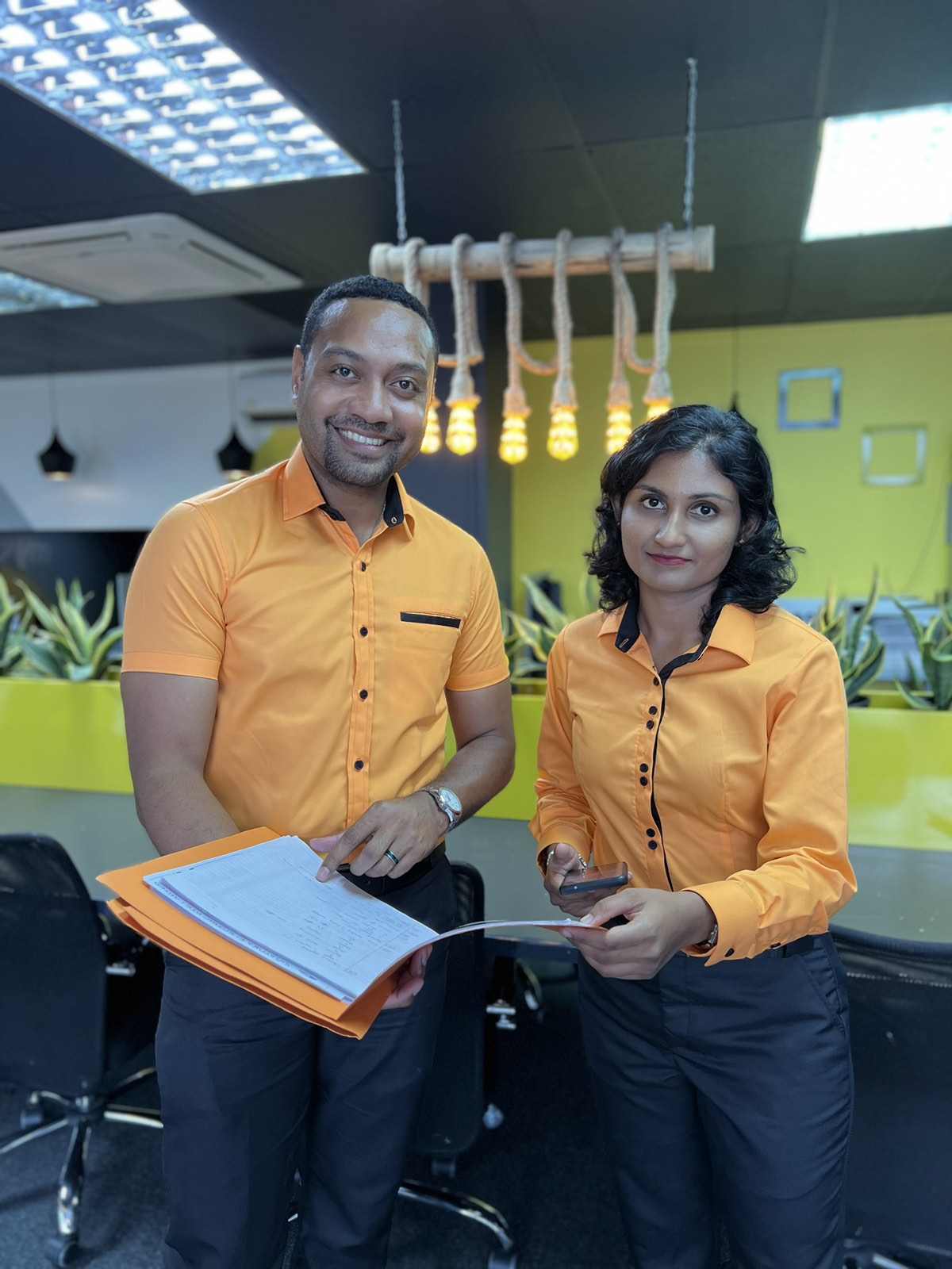Eleganza tailors in matching orange corporate uniforms reviewing an order book
